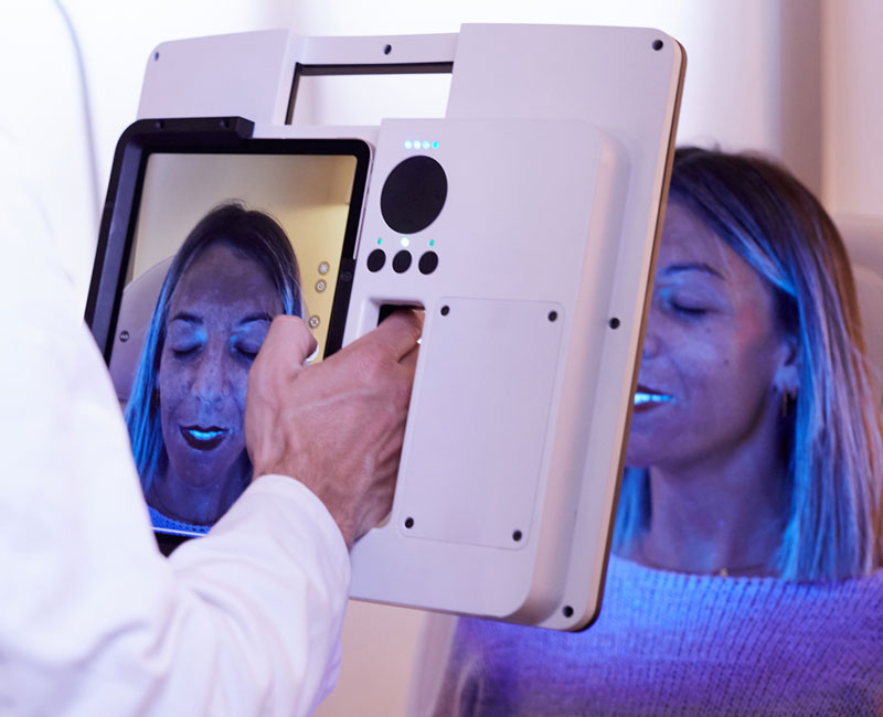 Profesional de la estética usando un dispositivo portátil fotos de dermatología y estética